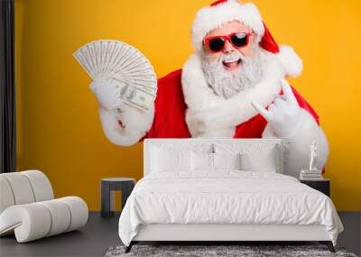 X-mas lottery win credit bank present for noel. Funky crazy hipster white bearded santa claus hold money fan show horned symbol enjoy deposit gift wear red hat isolated yellow color background Wall mural