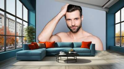 Young handsome naked man isolated on gray background touching his perfect hair and looking at camera Wall mural