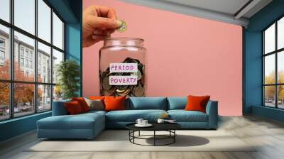 Female hand adding a pound coin to a glass jar. Period poverty concept. Wall mural