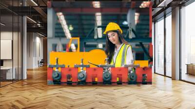 Happy professional beautiful Asian woman industrial engineer/worker/technician with safety hardhat use clipboard to inspect quality control of machinery in production steel manufacture factory plant Wall mural