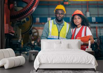 Portrait of professional happy smiling Black African American engineers, workers, technician man and woman wear hard hat, use clipboard discuss work in steel metal plant manufacturing factory industry Wall mural