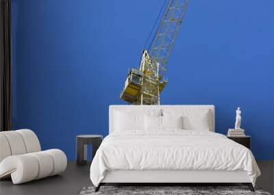 Yellow tower crane, blue sky background. Wall mural