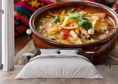 Close up of chicken enchilada soup in rustic bowl with cheese and tortilla strips on wooden table Wall mural