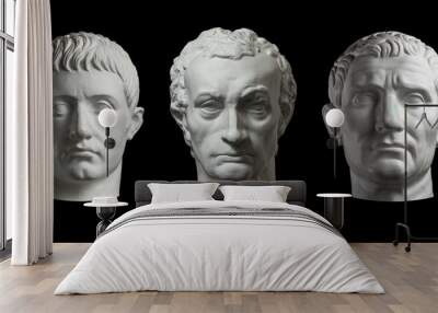 Three gypsum copy of ancient statue heads isolated on a black background. Plaster sculpture mans faces. Wall mural