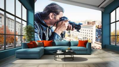 Investigator or private detective or reporter or paparazzi taking photo from balcony of building with professional camera Wall mural