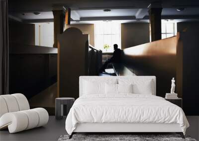 Silhouette of sinful man praying in church seating on pews Wall mural