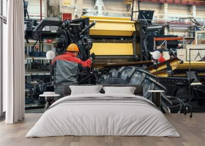 worker assembles agricultural vehicle combine harvester in industrial factory workshop. Wall mural