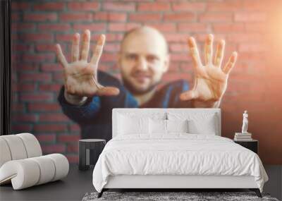 Young hypnotist or businessman in a jacket smiling and showing hands outstretched forward with palms Wall mural