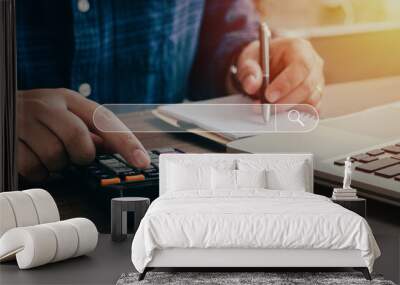 business man sitting searching for people who pay annual taxes Along with calculating with a calculator in order to record it as evidence Wall mural