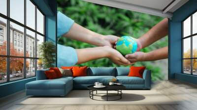 two people holding a globe green earth environmental conservation concept earth day on green bokeh background protect the environment and sustainability, save the world, the world, the world Wall mural