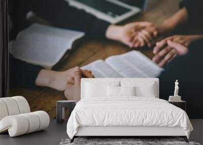 Christian group of people holding hands praying worship to believe and Bible on a wooden table for devotional for prayer meeting concept. Wall mural