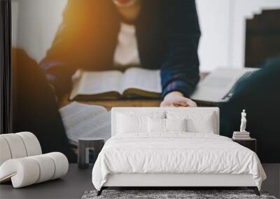 Christian group of people holding hands praying worship to believe and Bible on a wooden table for devotional for prayer meeting concept. Wall mural