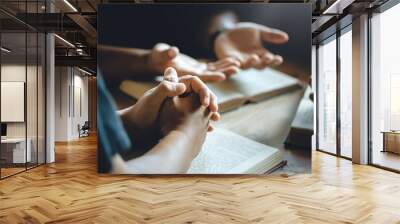 Christian group of people holding hands praying worship to believe and Bible on a wooden table for devotional or prayer meeting concept. Wall mural