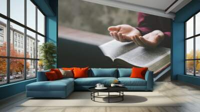 Christian hands folded for prayer with a holy bible and laptop on a wooden table in church for worship online to god in the morning. person pray with faith, Spirituality, and religion concept Wall mural