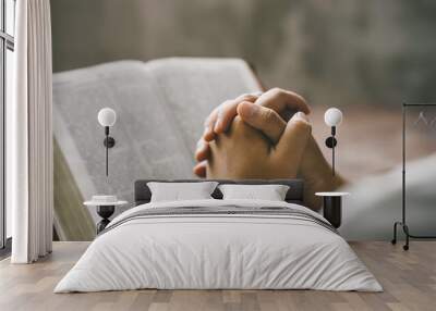 Christian hands folded for prayer with a holy bible on a wooden table in church for worship to god in the morning. person pray with faith, Spirituality, and religion concept Wall mural