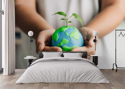 human hand holding young earth and plant in ecology and environment sustainable concept. Saving environment, save clean planet and net zero. World Earth Day and ESG and co2 concept Wall mural