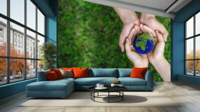 many hands person holding the earth on a green background to protect nature save and care world for  Wall mural