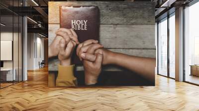 Top view christian of couple or group people holding hands praying worship together to believe and Bible on a wooden table for devotional for prayer meeting concept. Wall mural