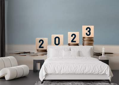 wooden cube year 2023 on top stack of coins with sky blue background and copy space. saving money an Wall mural