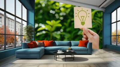 Hand holding a paper with a drawing of a light bulb, concept of idea and creativity. Wall mural