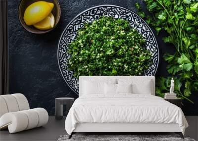 A plate of tabbouleh salad with parsley, lemon and a black stone background. Wall mural