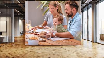 Family, food and lunch outdoor with child, mom and dad together for meal, wine and bonding at patio dining table. Baby, man and woman happy while eating outdoor in summer for healthy lifestyle Wall mural