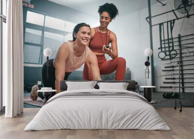 Personal trainer, exercise and stopwatch with a black woman coaching a client in a gym during her workout. Health, fitness or training and a female athlete ready to plank with a coach recording time Wall mural