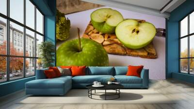 Tasty food in green. Two apples: one is whole, the other cut into two parts. Broccoli in a strange pyramid shape. Knife and board for cutting made of wood. Wall mural