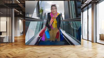 Senior lady with shopping bags in the mall automatic stairs. Wall mural