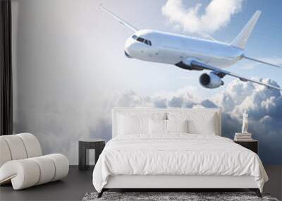 Airplane in the sky - cloudy but sunny day Wall mural