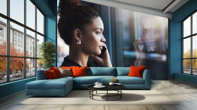 Success happens on her command. a young businesswoman talking on a cellphone in an office. Wall mural