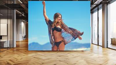 Summer Time for some SUNspiration. Shot of a young woman enjoying a carefree summers day at the beach. Wall mural