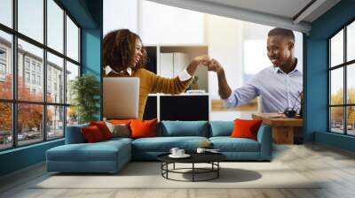 Bring it in partner. Shot of two young work colleagues greeting each other with a fist pump while being seated in the office. Wall mural