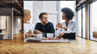 Give us difficult and well show you easy. Shot of a group of businesspeople sitting together in a meeting. Wall mural