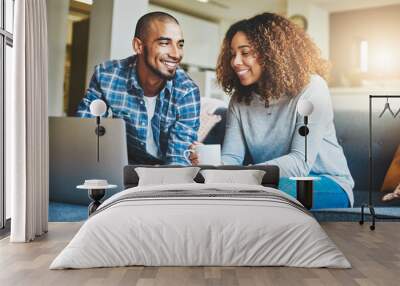 Home finance, savings and investment with a young couple working on a laptop in their living room. Man and woman calculating a household budget together while relaxing and drinking coffee on the sofa Wall mural