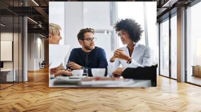 Success happens when a great team comes together. Shot of a group of businesspeople sitting together in a meeting. Wall mural