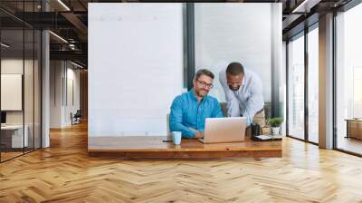 Two heads are always better than one. Shot of two businessmen working on a laptop in their office. Wall mural