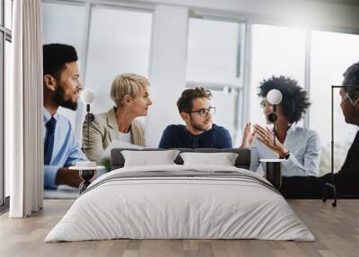 We will only win by working together. Shot of a group of businesspeople sitting together in a meeting. Wall mural