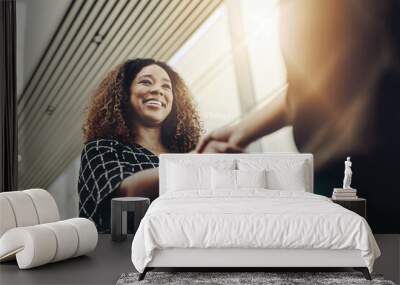 Welcome to the company. Low angle shot of an attractive young businesswoman shaking hands with an associate in a modern workplace. Wall mural