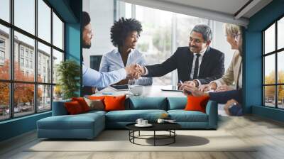 Welcome to the team. Cropped shot of a diverse group of businesspeople having a meeting in the office and shaking hands. Wall mural