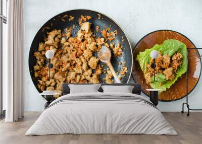 Top view of frying pan with cooked/sauteed ground turkey with shredded carrots and sweet soy sauce and lettuce cups finger food on a brown pottery plate. Overhead, close up.  Wall mural