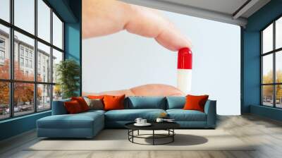 Close up of a hand holding a white and red oblong pill, health and medication, drugs concept Wall mural