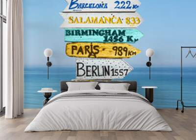 Colorful directions signs on the beach to different cities and countries of the world including Madrid, Paris, Berlin, Praga. Travel concept. Wall mural