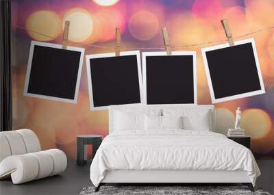 Four blank instant photo frames hanging on a rope, on holiday lights bokeh background Wall mural