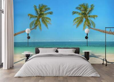 Leaning palm trees over a beach with turquoise sea Wall mural