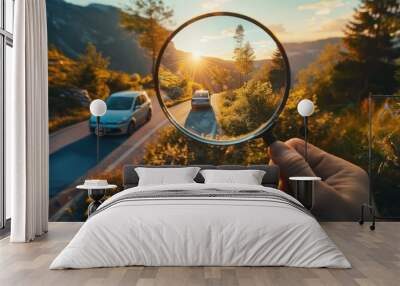 Concept hand holding magnifying glass, capturing car and beautiful mountain views through the glass. Wall mural