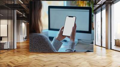 Portrait of a woman holding a mobile phone with a blank desktop white screen for mockup. Wall mural