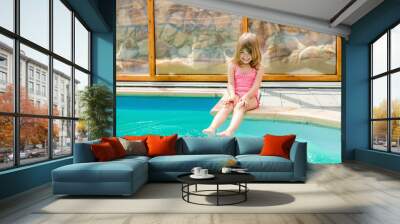 happy little girl sitting by the pool and having fun in the water feet Wall mural