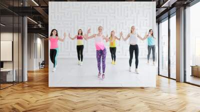 Young women in colorful sportswear at dance fitness class in white fitness studio Wall mural