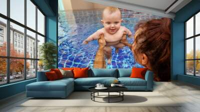 Crop shot from above parent carrying little infant kid in water of pool learning to swim Wall mural